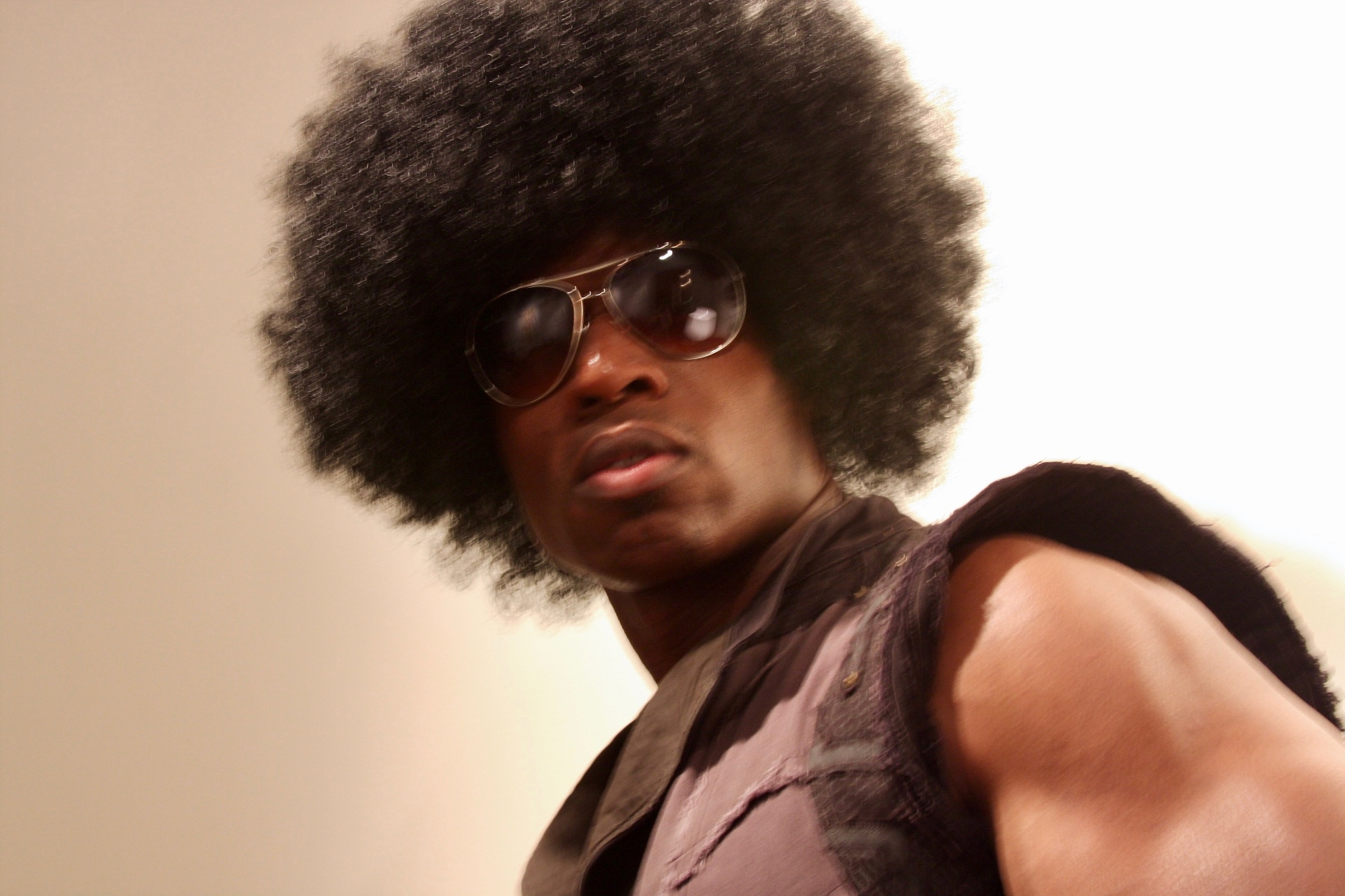 Lawrence Beamen in character with an afro wig and aviator sunglasses